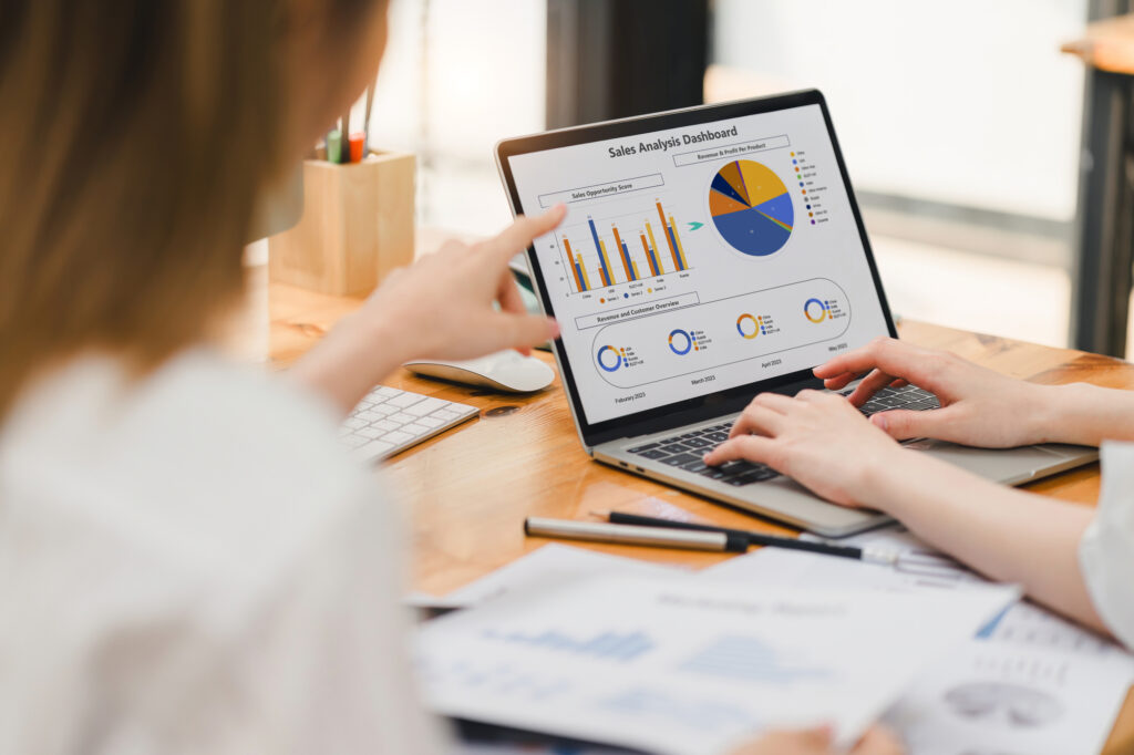 Professional working intensively on a financial analysis with colorful charts and data spreadsheets displayed on a laptop.